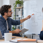 AI illustration of two colleagues discussing blank connected boxes on a whiteboard beside a laptop.